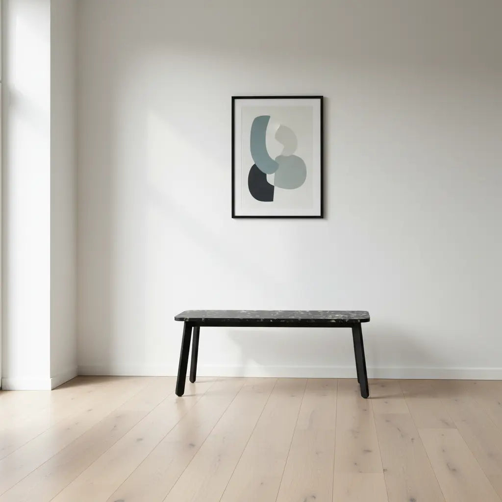 Eco-friendly HDPE bench with black terrazzo panel top in a bright minimalist interior with oak flooring and framed wall art