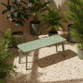 Sage green recycled plastic bench surrounded by potted greenery on a sunlit terrazzo patio