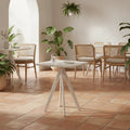 Square white polymer table with recycled panel top in a HoReCa space with terracotta flooring and rattan chairs